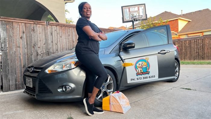 Dee Reed leaning on the grey Poop Savvy service car with the company magnet and phone number on the door